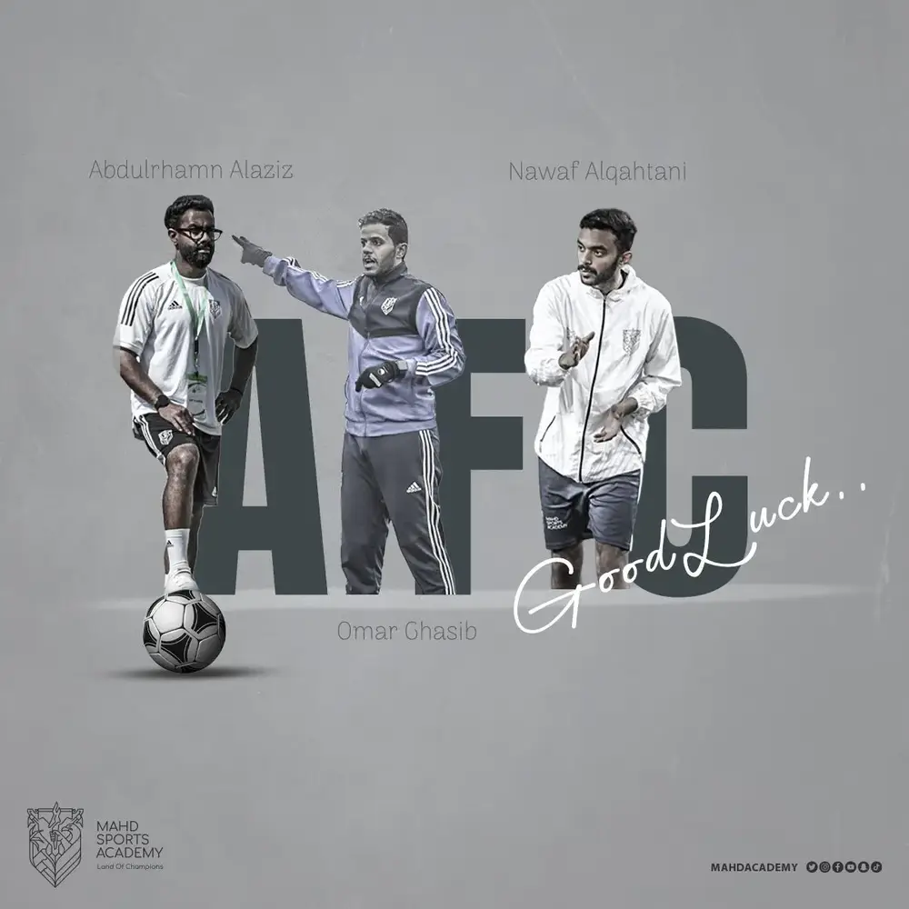 ثلاثة مدربين يرتدون زي رياضي يقفون بجانب كرة قدم. المدرب الأول يرتدي نظارات وقميصاً أبيض، ويقع على جهة اليسار، بينما المدرب الثاني يرتدي سترة رياضية زرقاء في المنتصف ويشير بيده. المدرب الثالث على اليمين يرتدي سترة بيضاء ويقوم بإشارة. الخلفية تحتوي على عبارة 